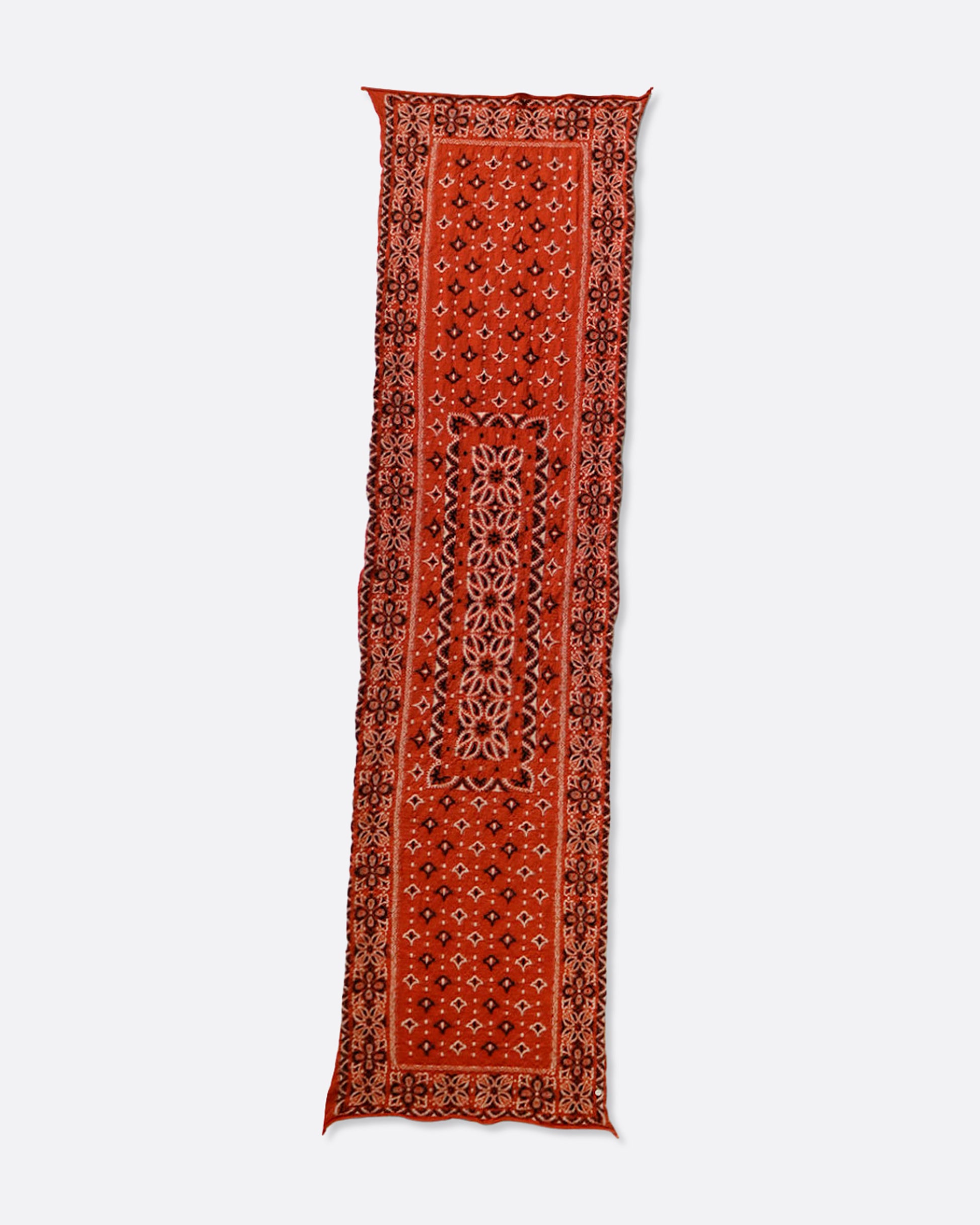 A red compressed wool scarf with a classic bandana pattern, shown lying flat.