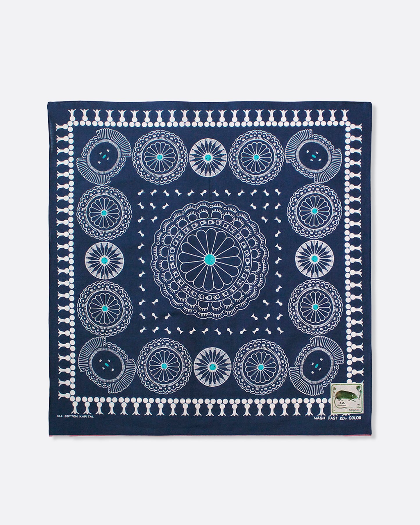 A navy selvedge bandana with a pattern of turquoise- centered conchos. Shown lying flat.