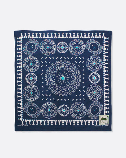 A navy selvedge bandana with a pattern of turquoise- centered conchos. Shown lying flat.