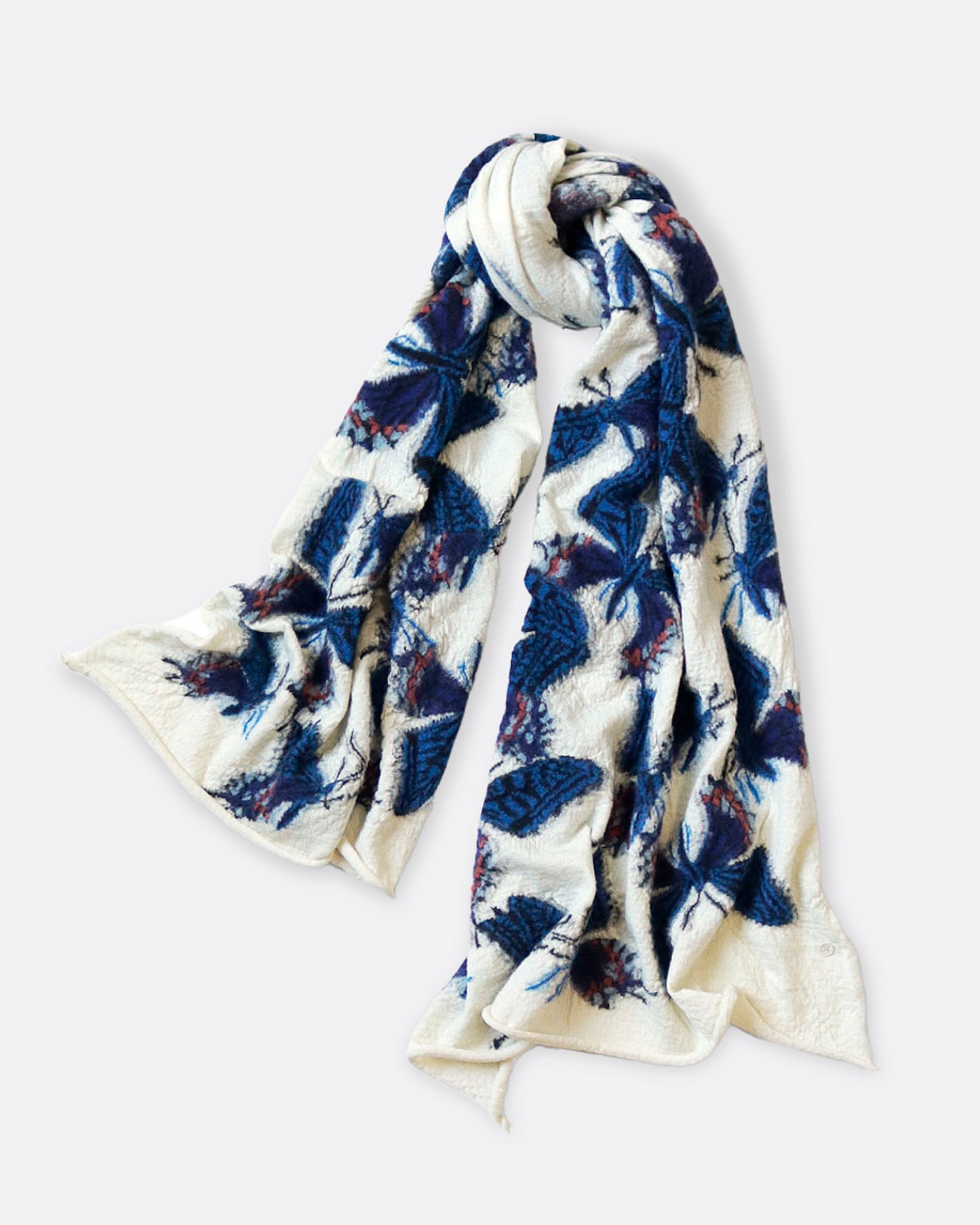 A white compressed wool scarf with blue butterflies all over it, shown looped.