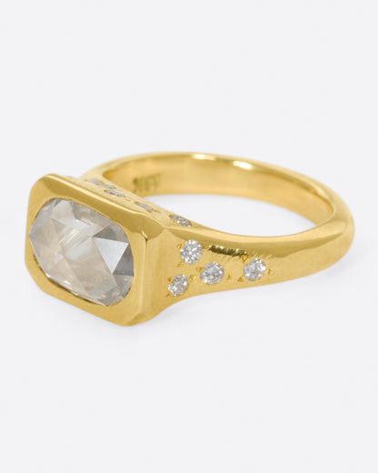 Yellow gold oval diamond ring, side view with the oval diamond facing left and star-set diamonds along the shank