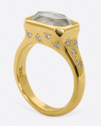 Yellow gold oval diamond ring, angled view showing the height of the bezel and diamonds scattered down the shank