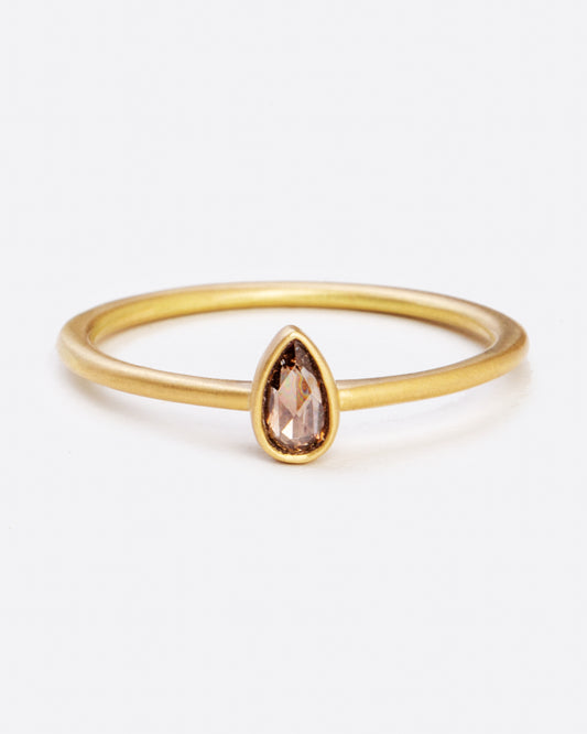 A yellow gold ring with a bezel set teardrop shaped diamond. Shown from the front.