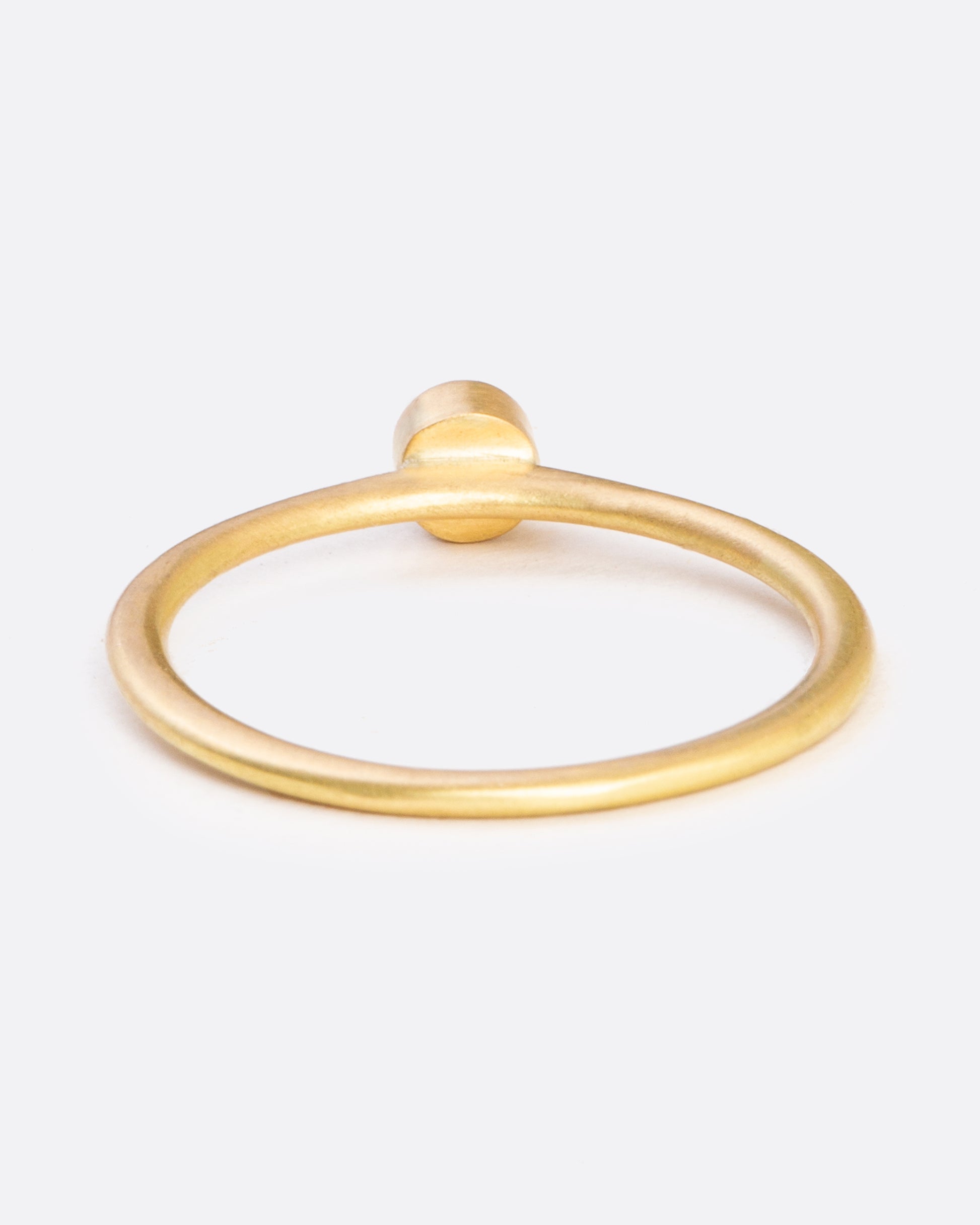 A yellow gold ring with a bezel set round diamond. Shown from the back.