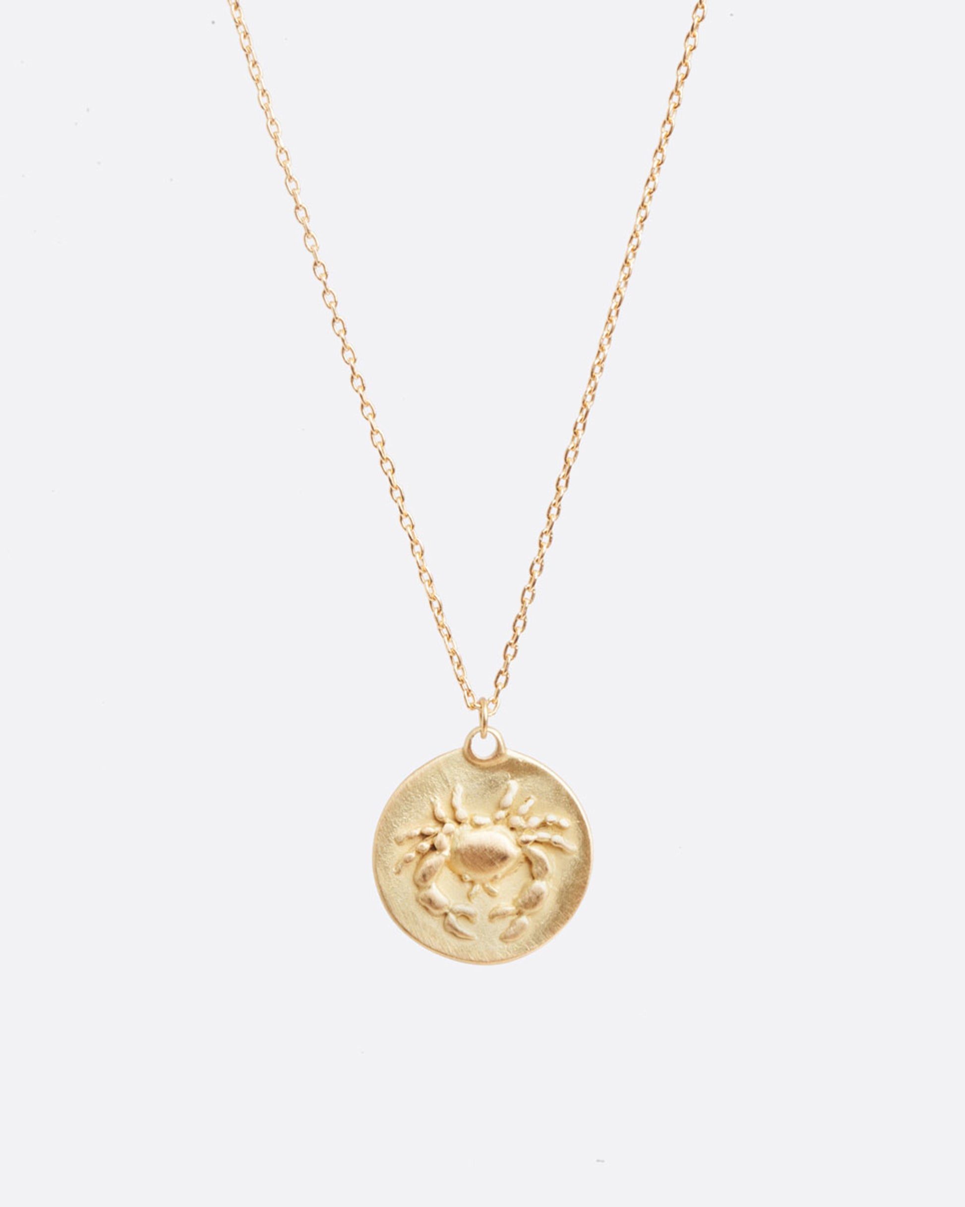 A yellow gold necklace with a round pendant with your choice of zodiac symbol.