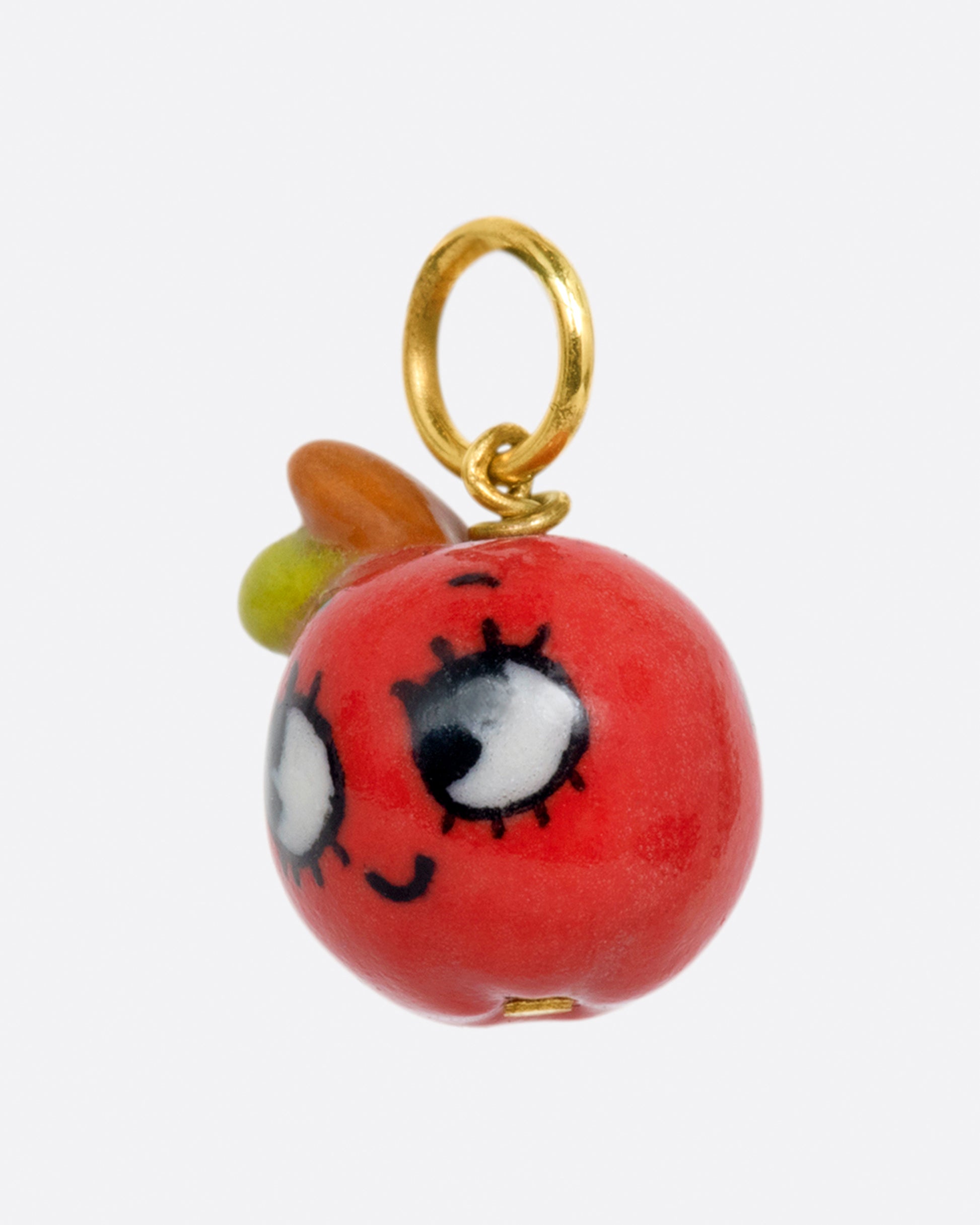A handmade porcelain 3D apple charm with a smiling face and a yellow gold bail.