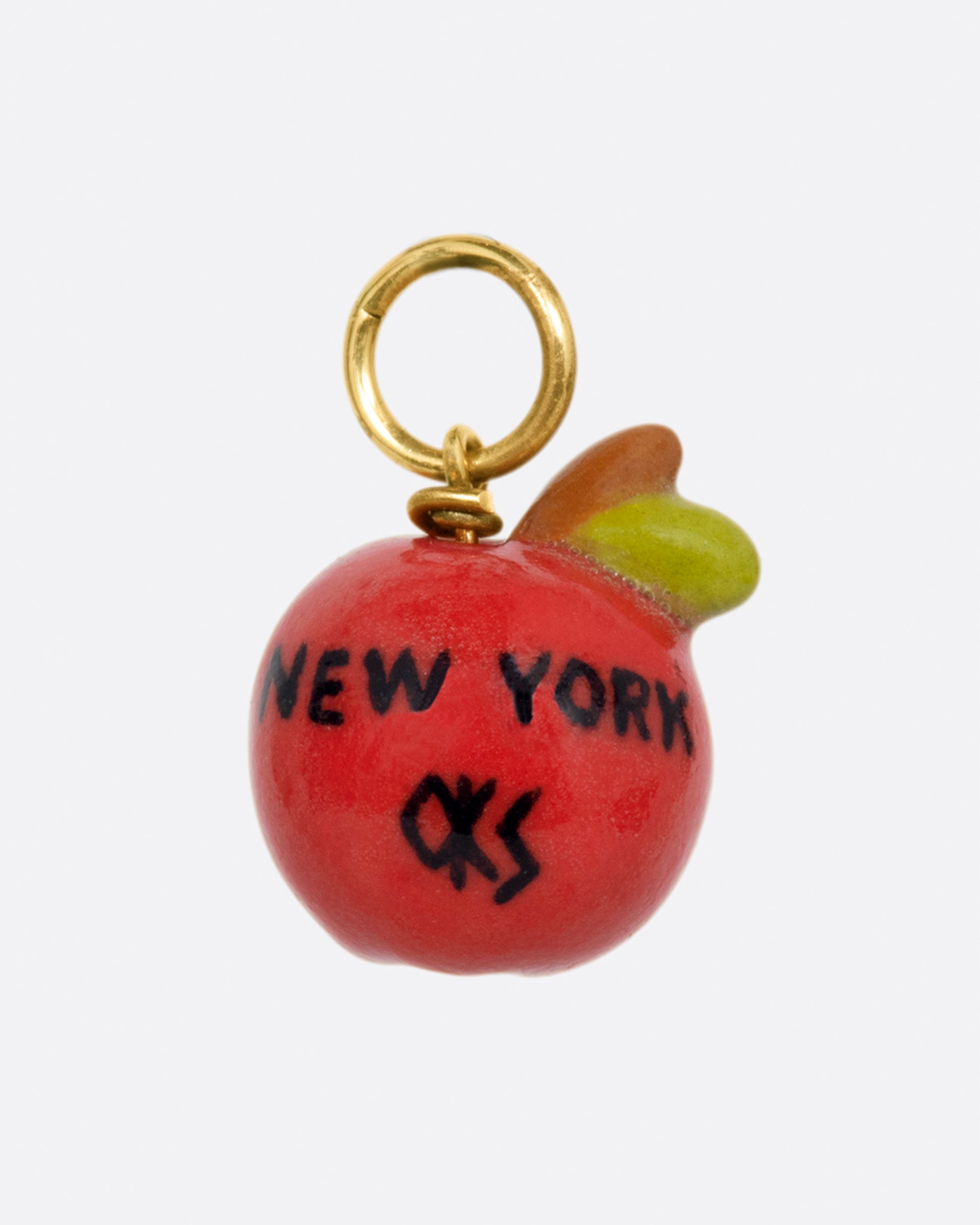 A handmade porcelain 3D apple charm with a smiling face and a yellow gold bail.