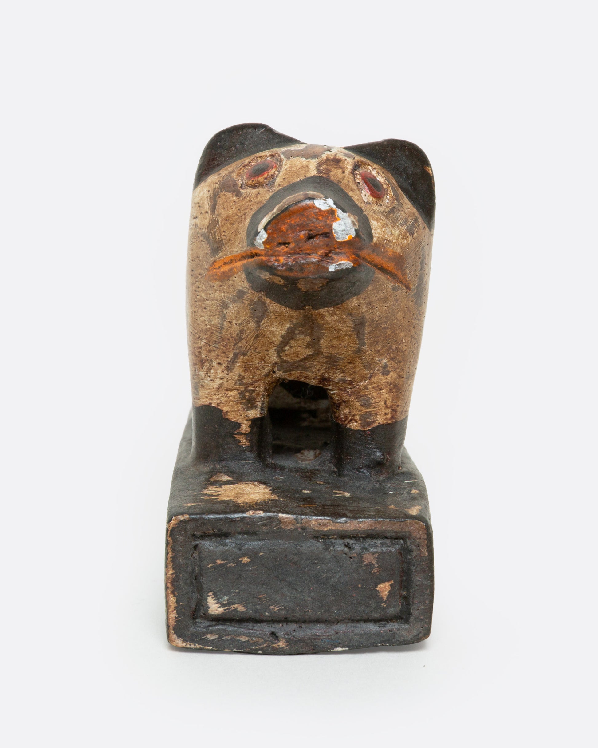 A hand carved wooden door stop with a spotted pig, shown from the front.