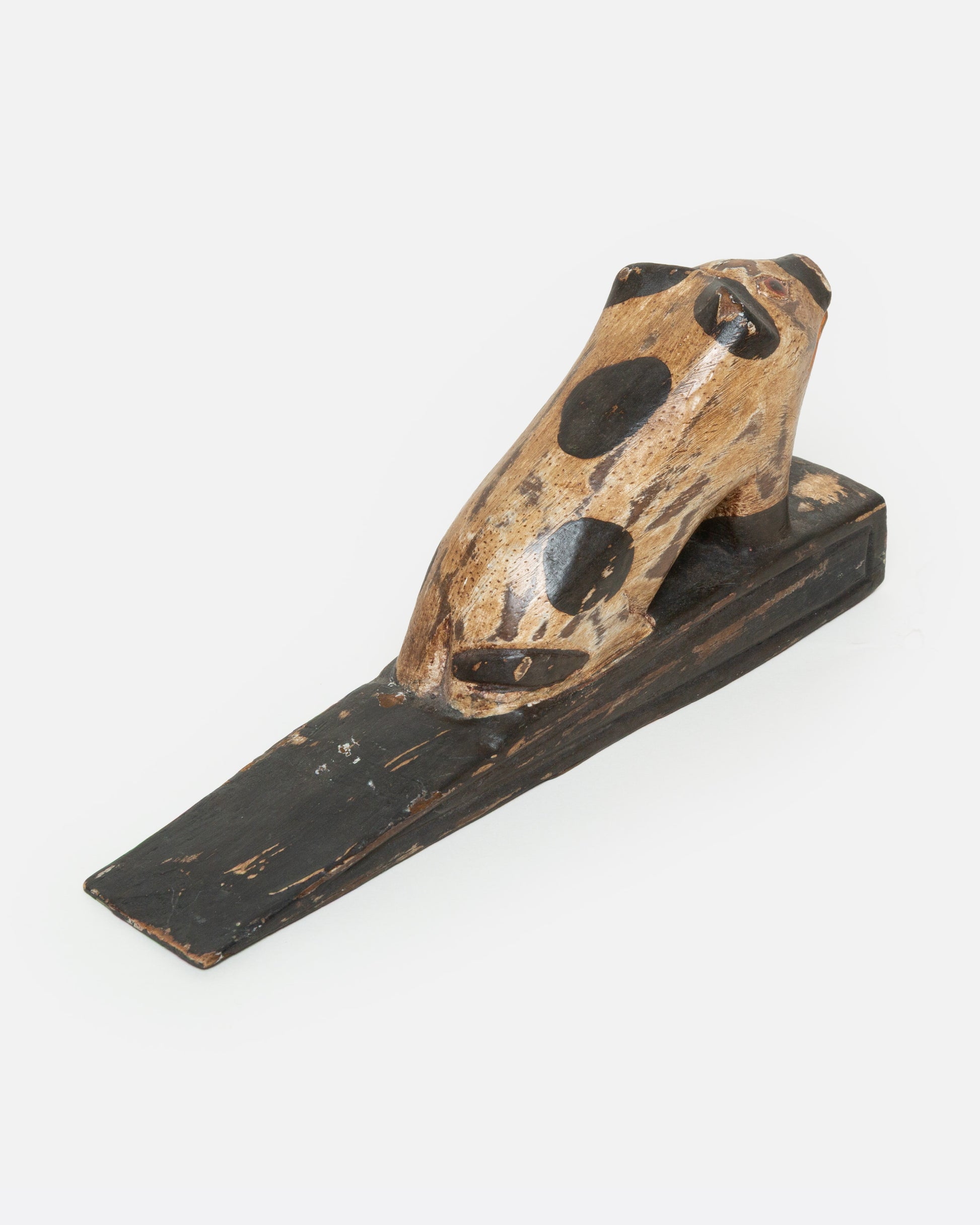 A hand carved wooden door stop with a spotted pig, shown from the back.
