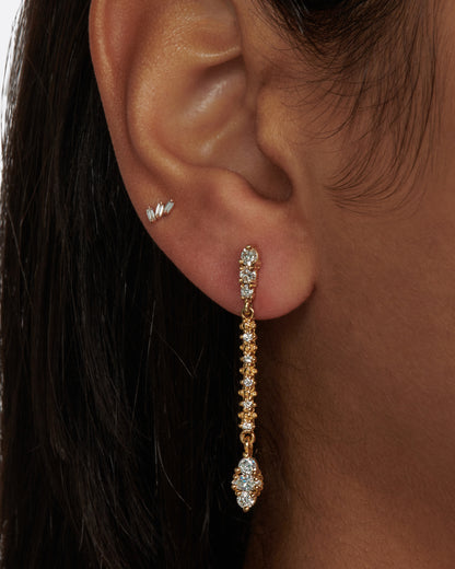 A long yellow gold earring with diamonds throughout. Shown on a person.