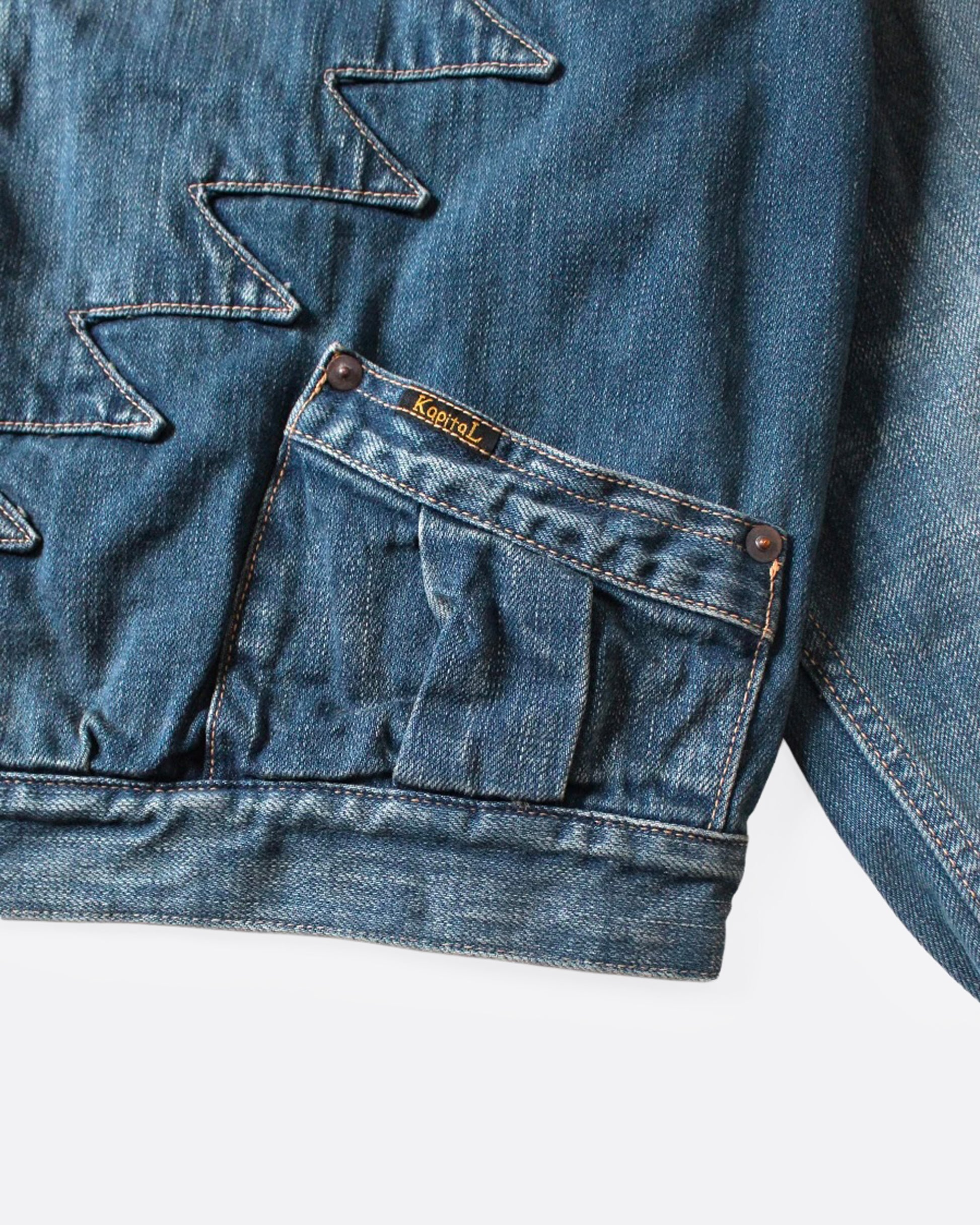 A close up of a light blue denim jacket with Chimayo-inspired embroidery across the chest and at each elbow, button closures, and functional back cinch. 