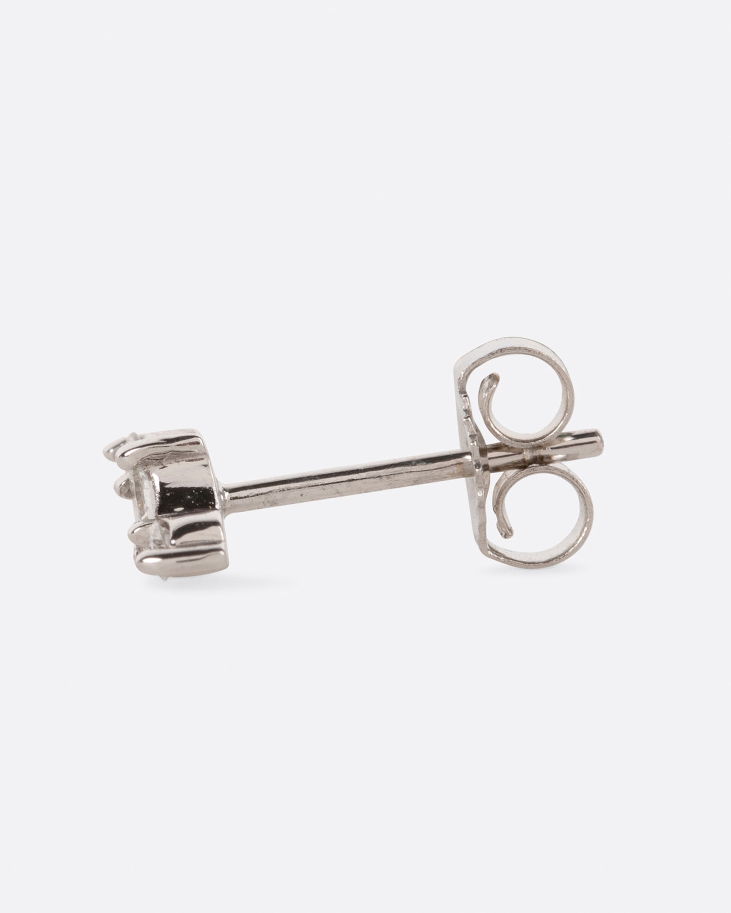 A white gold stud earring with a princess cut diamond at the center and two round diamonds on either side. View from the side.