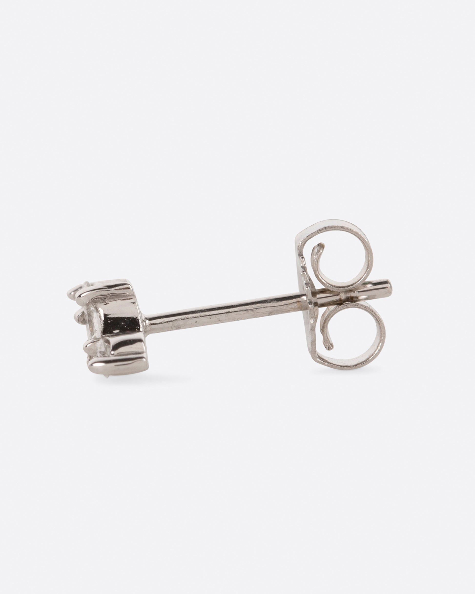 A white gold stud earring with a princess cut diamond at the center and two round diamonds on either side. View from the side.