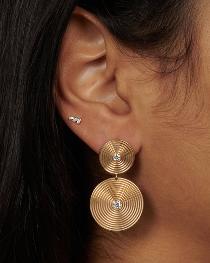Yellow gold diamond disc drop earrings worn on an ear
