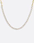 A yellow gold, oval link chain necklace with four inches of contrasting white diamonds, shown from the front.
