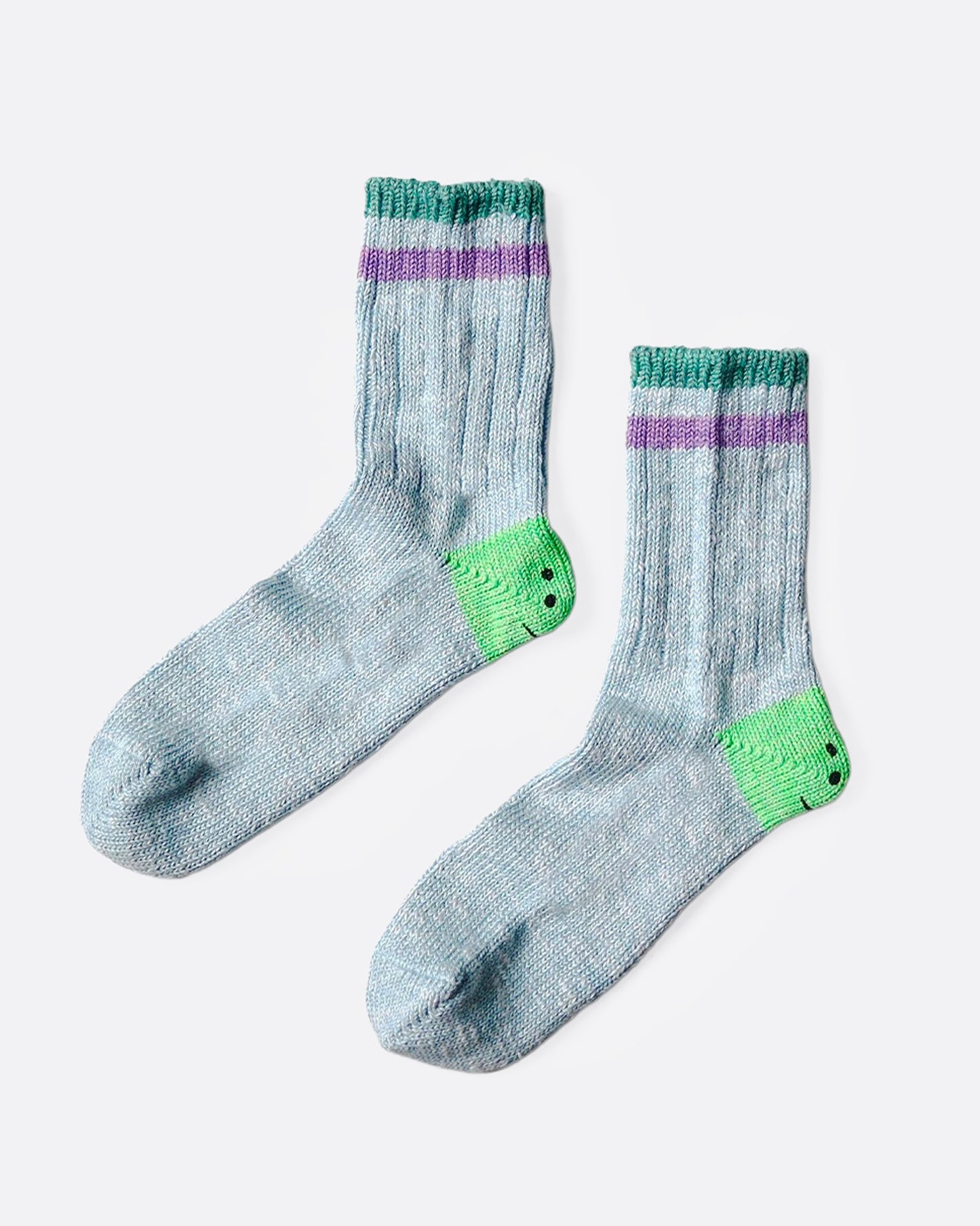 A pair of blue socks with green smiley heels, and green and purple stripes on each ankle. Shown from the side.