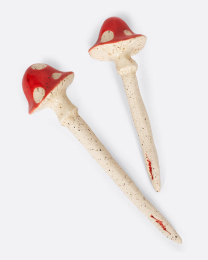 Sara White Ceramics magic mushroom plant sculptures, two red-capped mushrooms with white spots on speckled stakes