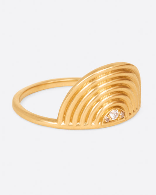A yellow gold ring with a semi- circle spiral with three diamonds at its center. Shown from the side.