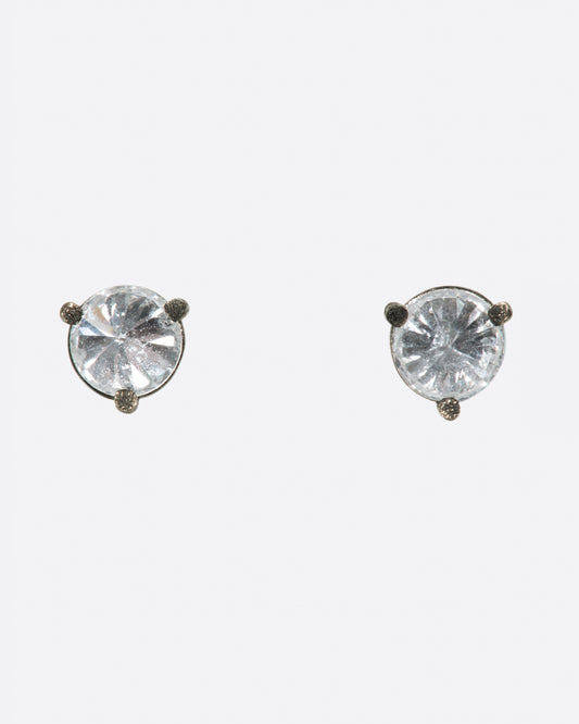 A pair of solitaire stud earrings with round inverted diamonds set in darkened white gold settings. Shown from the front.