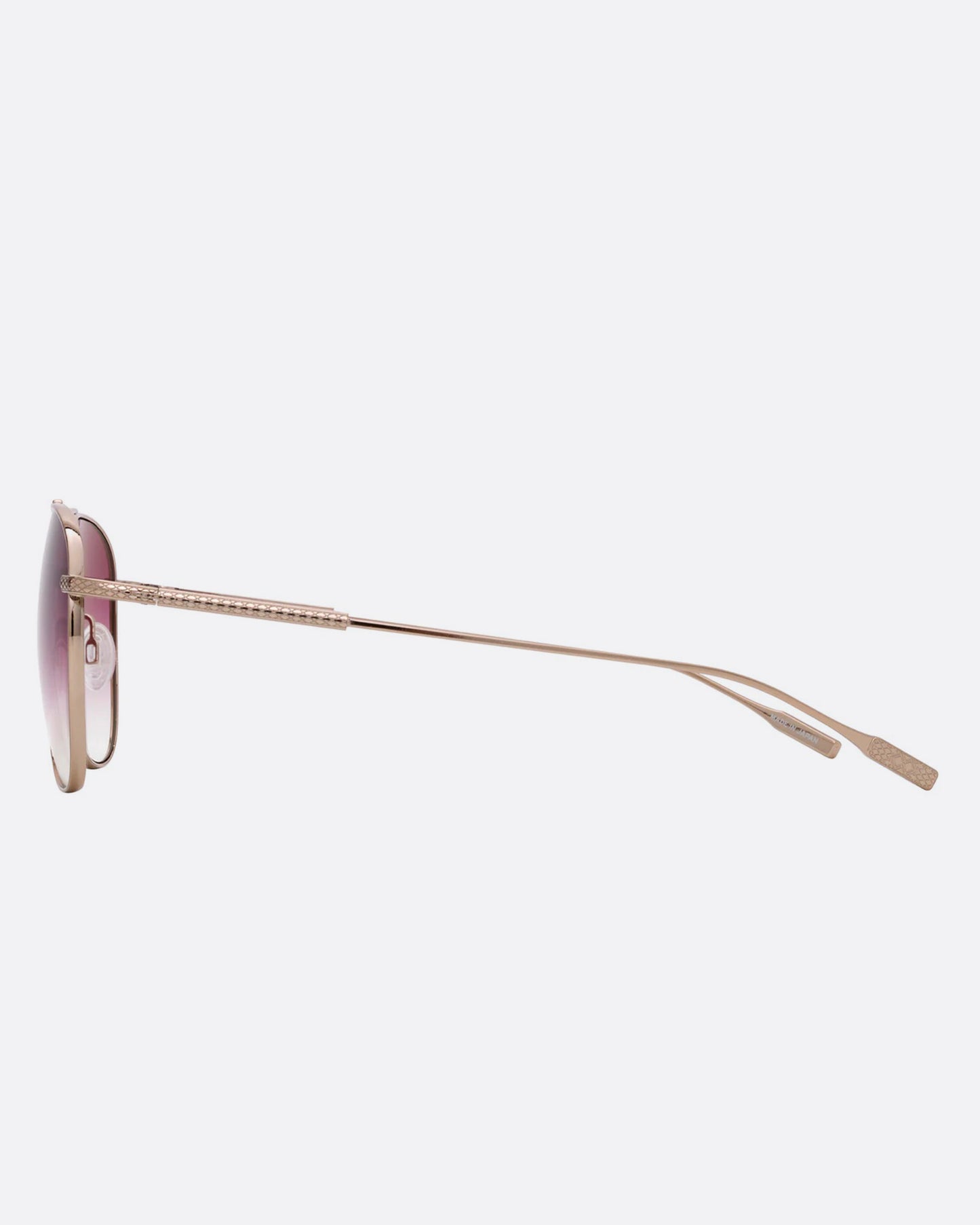 A pair of aviator sunglasses with pink gradient lenses. Shown from the side..