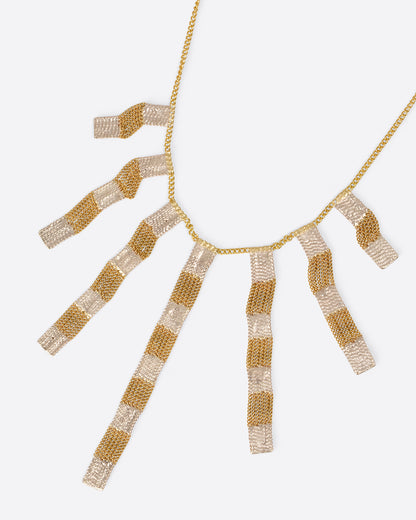 A yellow gold cable chain necklace with seven clusters of cable chain fringe with alternating bits of silver solder. Shown from the front.