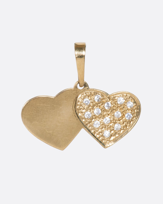 A yellow gold double heart charm with pavé diamonds over a stipple finish on one heart. Shown from the front.