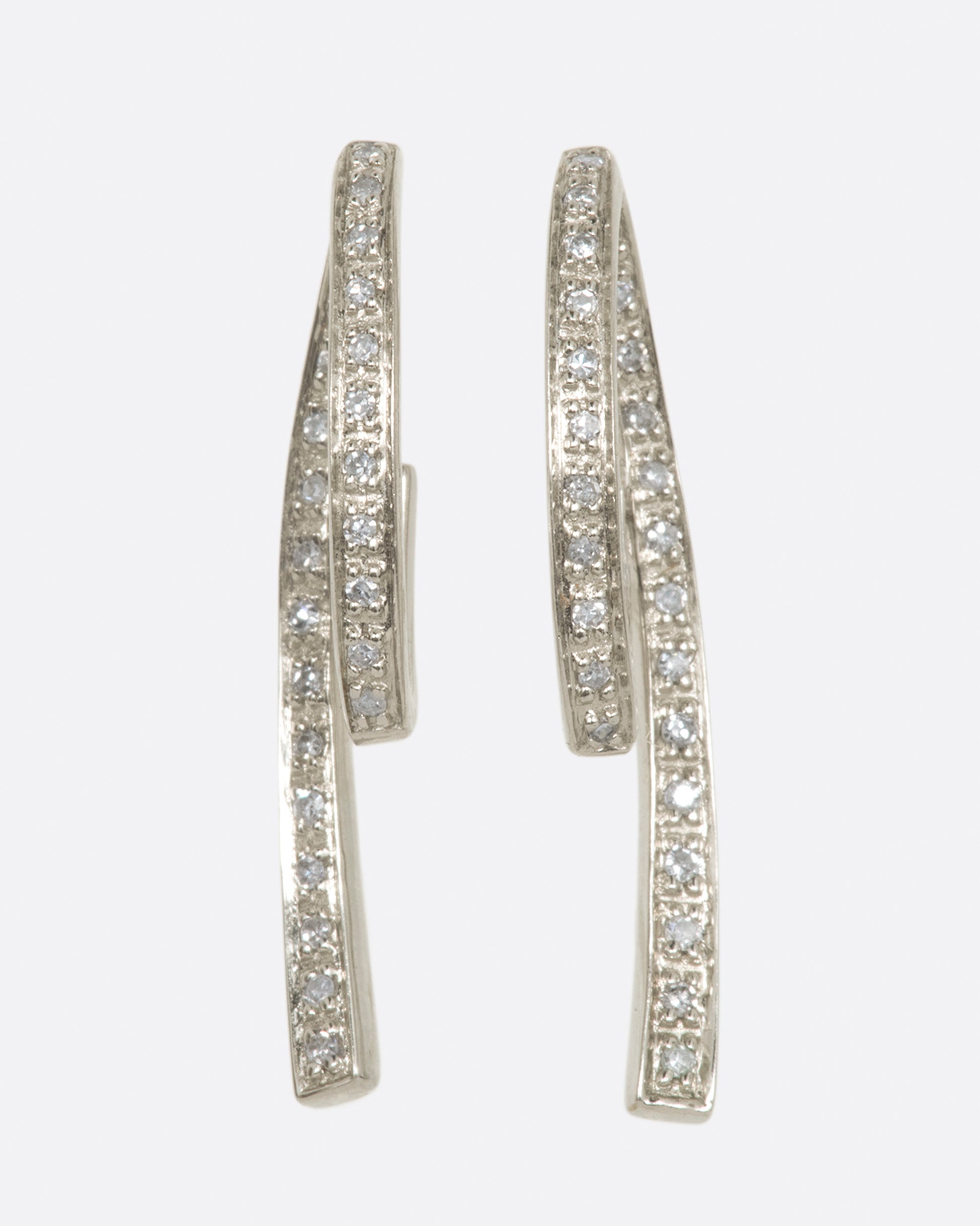 A pair of white gold, 3D loop de loop earrings, lined with diamonds.