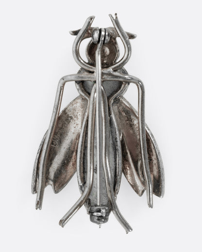 A silver wasp pin, shown from the back.