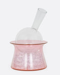 A glass decanter with a clear bottle and pink base, shown from the front.