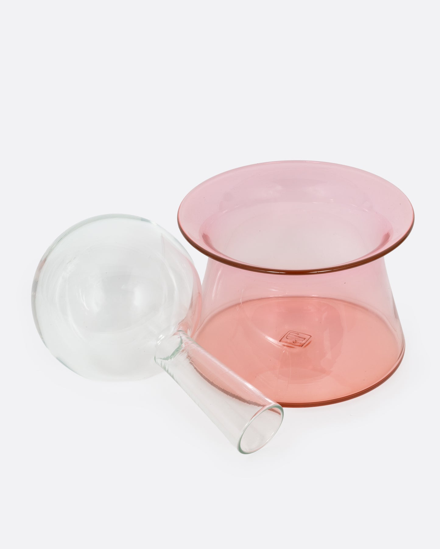 A glass decanter with a clear bottle and pink base, shown with the bottle on its side.