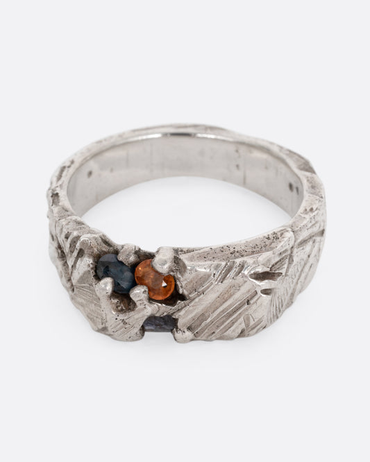 A silver ring with a citrine and amethyst embedded in it, shown from the front.