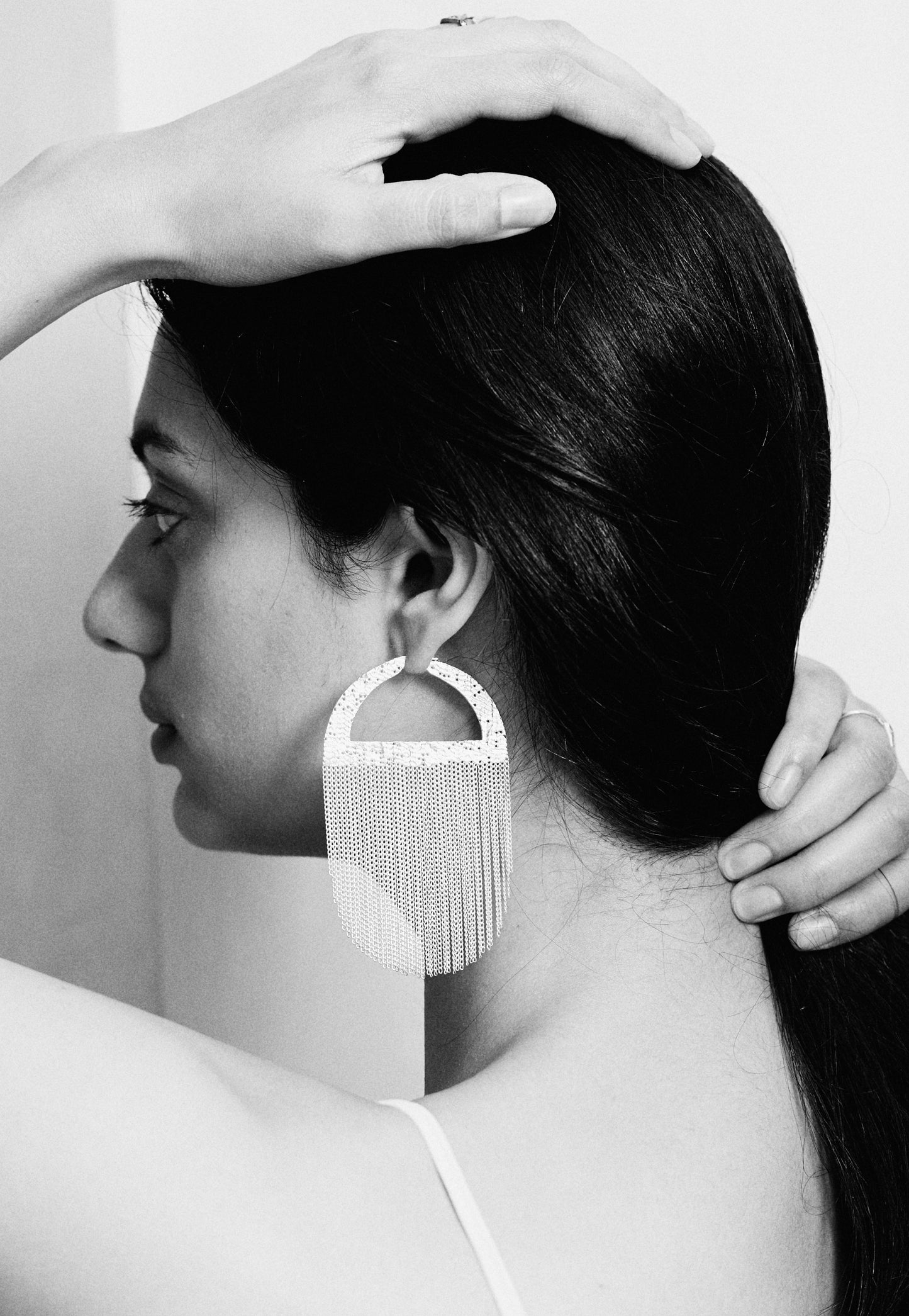 womans ear with hoop earrings with long chains hanging from them