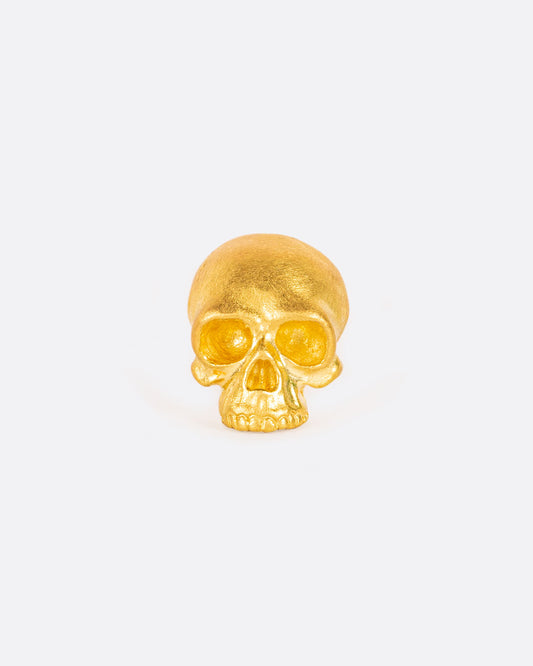 A solid yellow gold skull stud earring. Shown from the front.