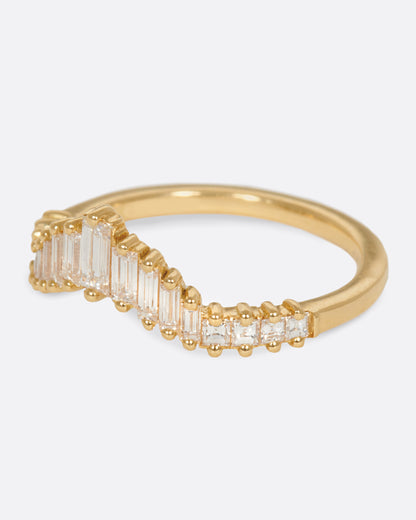 A curved crown ring lined with baguette diamonds. Shown from the side.