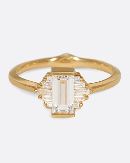 A large diamond baguette sits at the center of this ring, flanked by five additional baguettes on either side. Shown from the front.