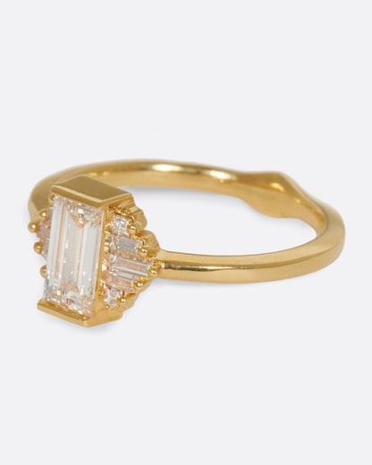 A large diamond baguette sits at the center of this ring, flanked by five additional baguettes on either side. Shown from the side.