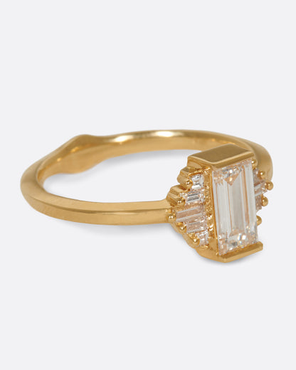 A large diamond baguette sits at the center of this ring, flanked by five additional baguettes on either side. Shown from the side.