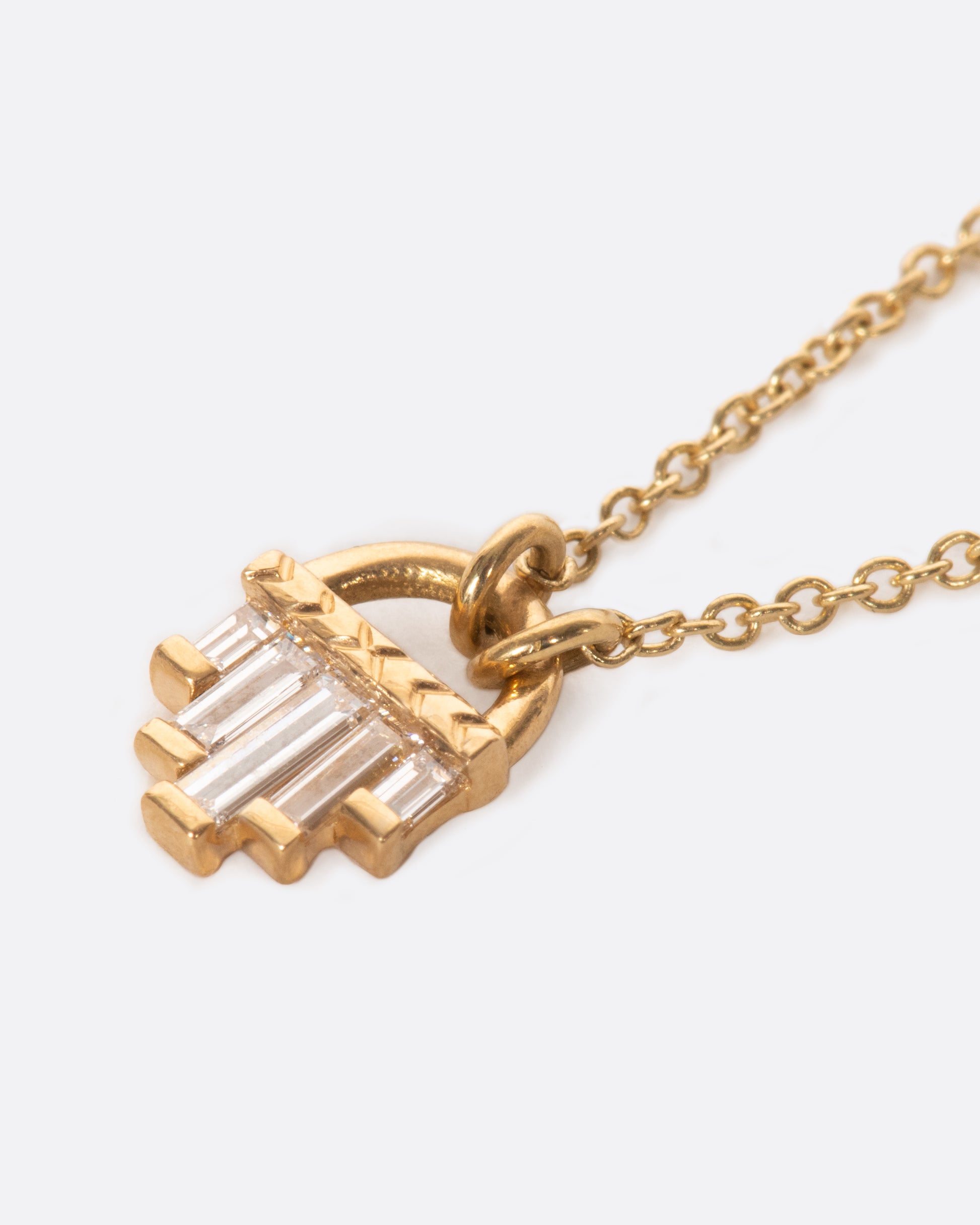 A curved gold pendant necklace with five diamond baguettes.