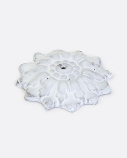 A white ceramic incense holder in the shape of a flower with a center hole. Shown lying flat from the front.