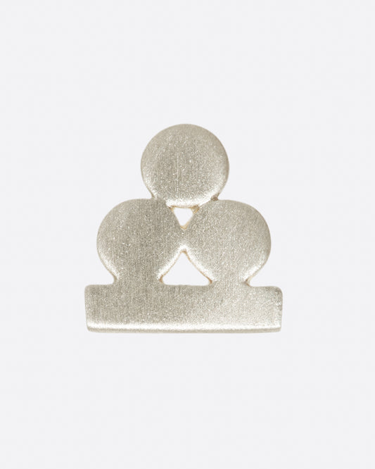 A silver stud earring with three matte circles sitting on a bar. Shown from the front.