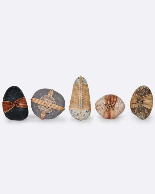 A group of five blessing stones, each wrapped and woven with grasses . Shown from the front standing up.