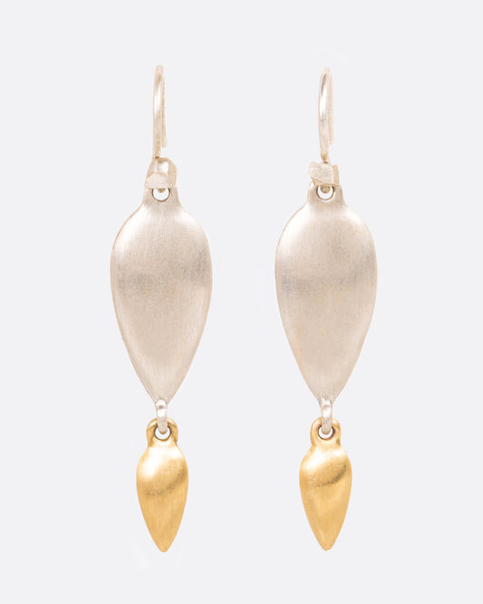 A pair of sterling silver teardrop earrings with yellow gold teardrop dangles at the bottom. Shown from the front.