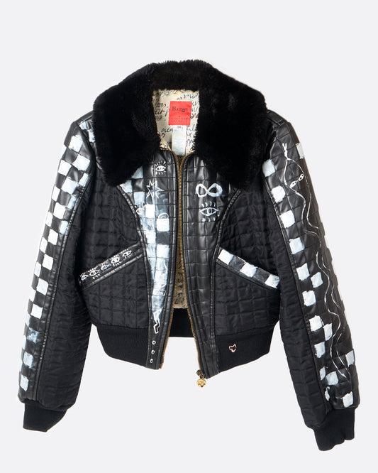 A hand painted black and white checked jacket with a faux fur collar and zip front. Shown from the front.