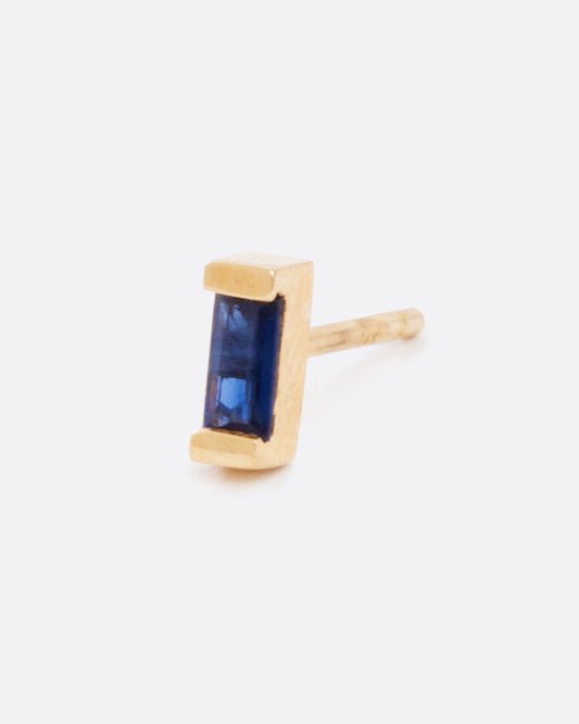 A single earring with a small blue sapphire baguette set in yellow gold. Shown diagonally from the side.