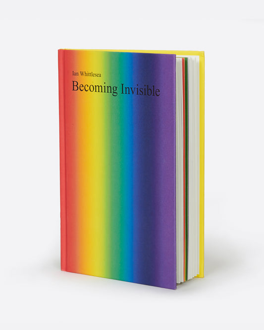 A book called Becoming Invisible by Ian Whittlesea with a striped rainbow front cover. Shown standing up at an angle from the front.