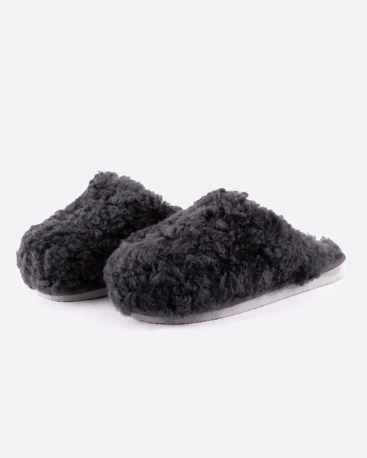 A pair of Jenny sheepskin slippers in charcoal gray, shown from the side.