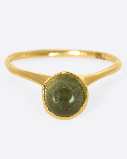 A yellow gold ring with a green tourmaline cabochon, shown from the front.