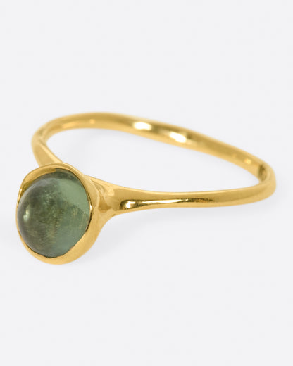 A yellow gold ring with a green tourmaline cabochon, shown from the side.