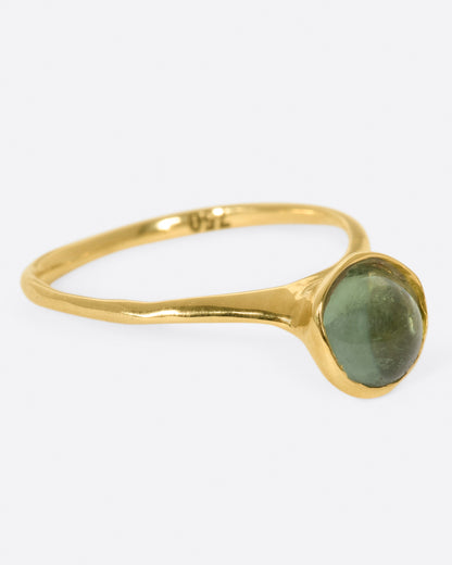 A yellow gold ring with a green tourmaline cabochon, shown from the side.