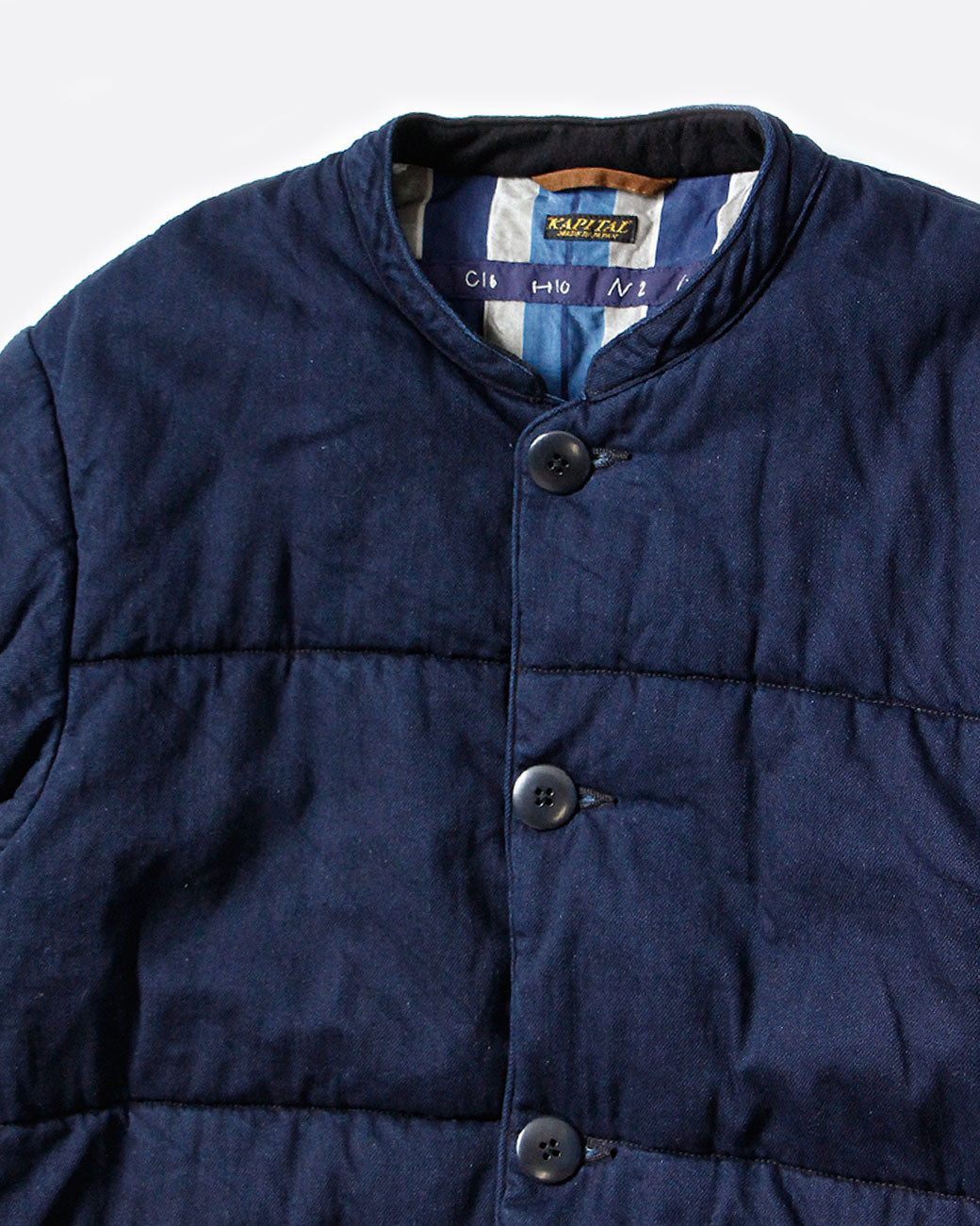 A navy quilted denim jacket with button closure and two front pockets. Shown close up from the front.